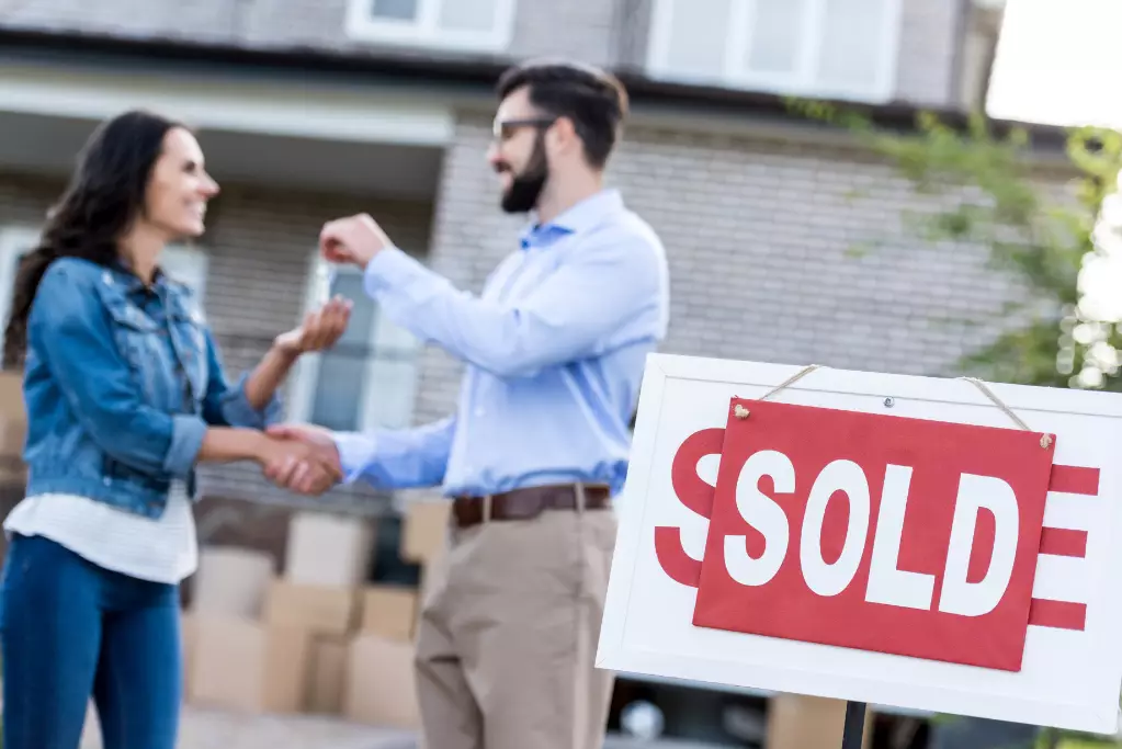 Woman buying new house with sold signboard on foreground